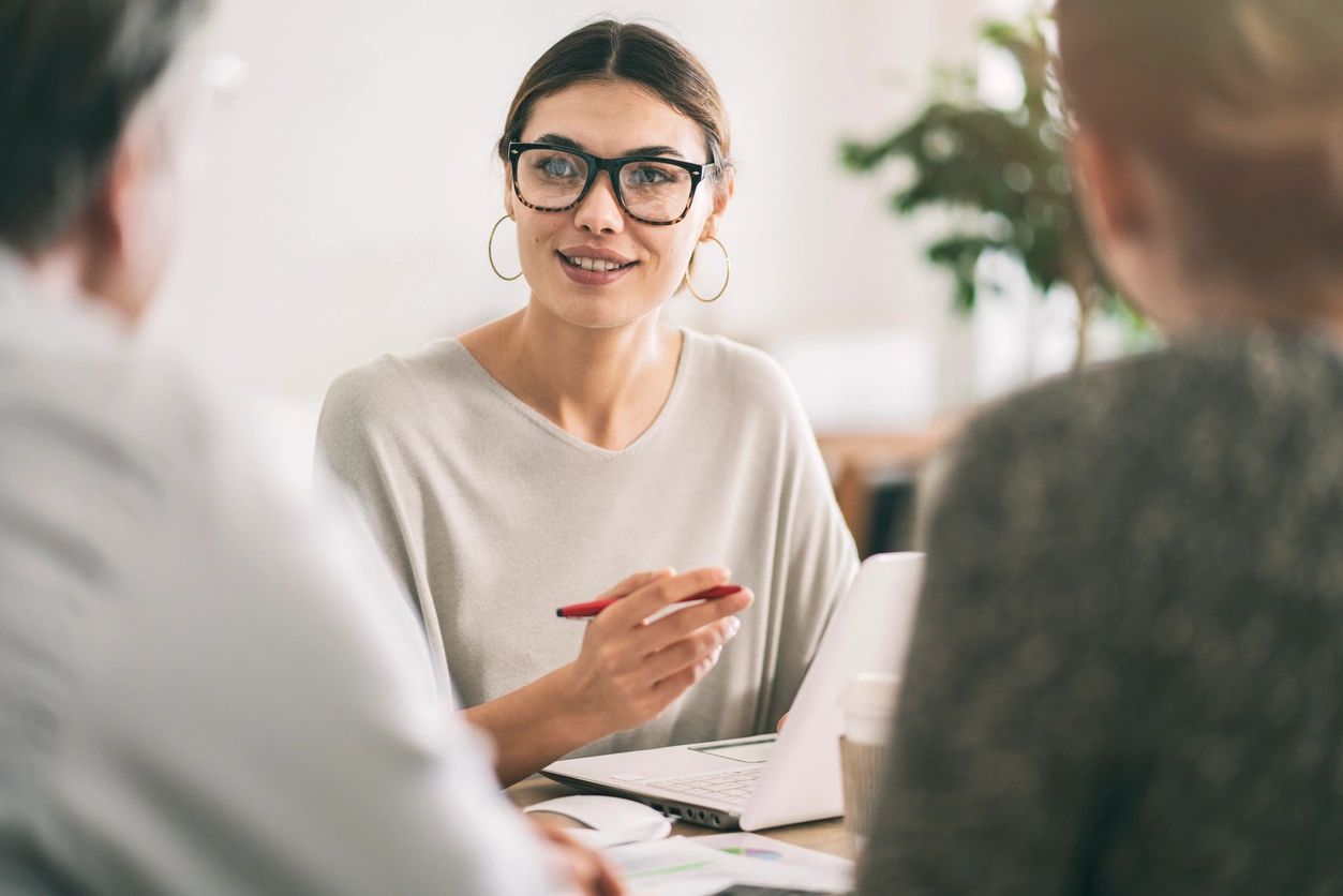 Woman with glasses speaking to 2 clients